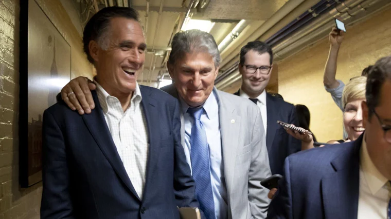 Mitt Romney (izq.) y el senador demócrata de Virginia Occidental Joe Manchin caminan juntos al salir de una reunión de senadores bipartidistas en el Capitolio en Washington, en una foto de archivo