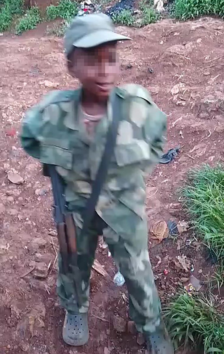 En este captura de un vídeo, se ve un niño, uniformado con varias tallas más grandes, armado con un fusil