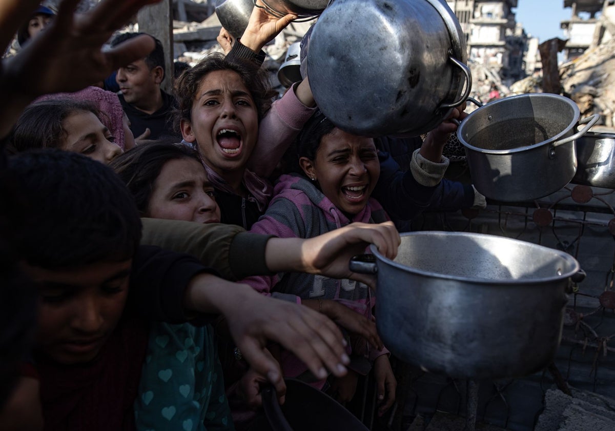 Niños palestinos hacen fila para recibir comida en una cocina benéfica al norte de la Franja