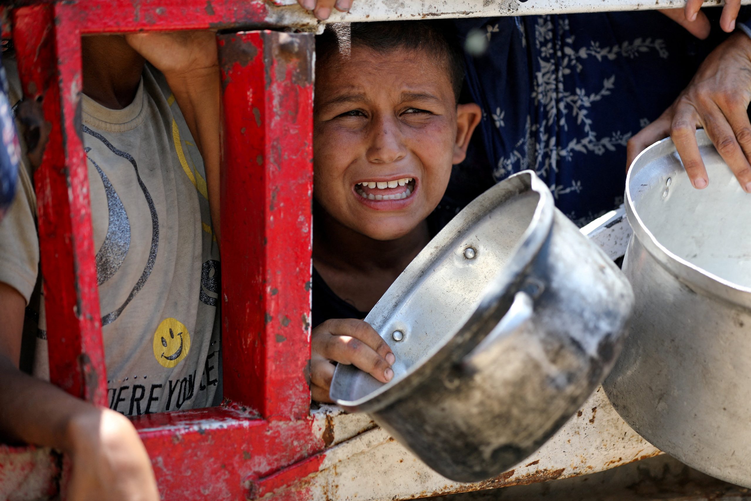 Niños gazatíes se reúnen para recibir comida de una cocina de caridad