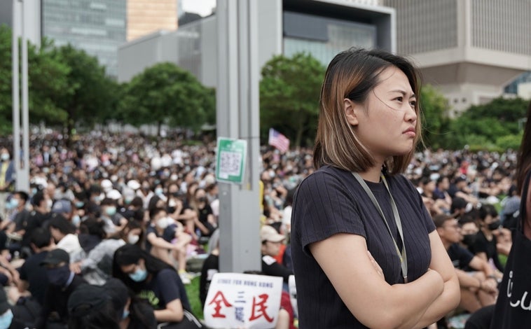 Imagen principal - Carmen Lau: «Hay gente en la diáspora y sobre el terreno trabajando para que el movimiento siga adelante». Arriba, Carmen Lau, activista hoy en el exilio, durante las protestas prodemocracia en 2019 en Hong Kong. Abajo, durante la campaña de las elecciones municipales de 2019 y a la derecha, una copia de las cartas remitidas a los vecinos de Carmen Lau, en la que se ofrecía un millón de dólares hongkoneses de recompensa por su entrega a la embajada china