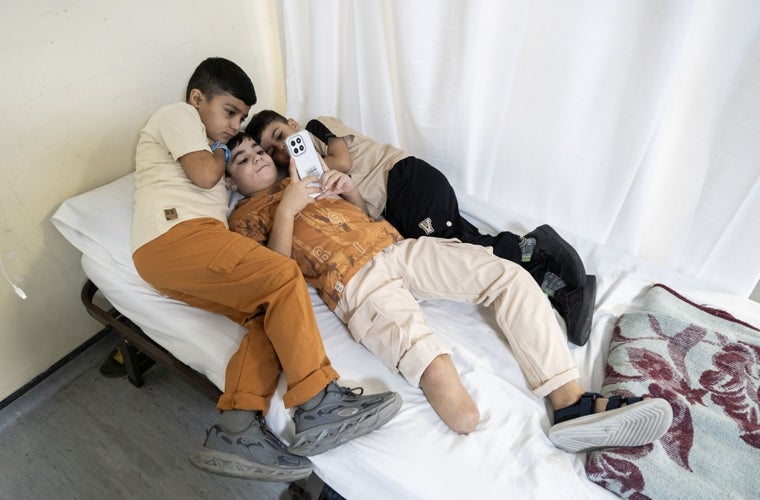 Amir Al-Daour, de Gaza, junto a sus hermanos Aser y Adam en su habitación del hospital