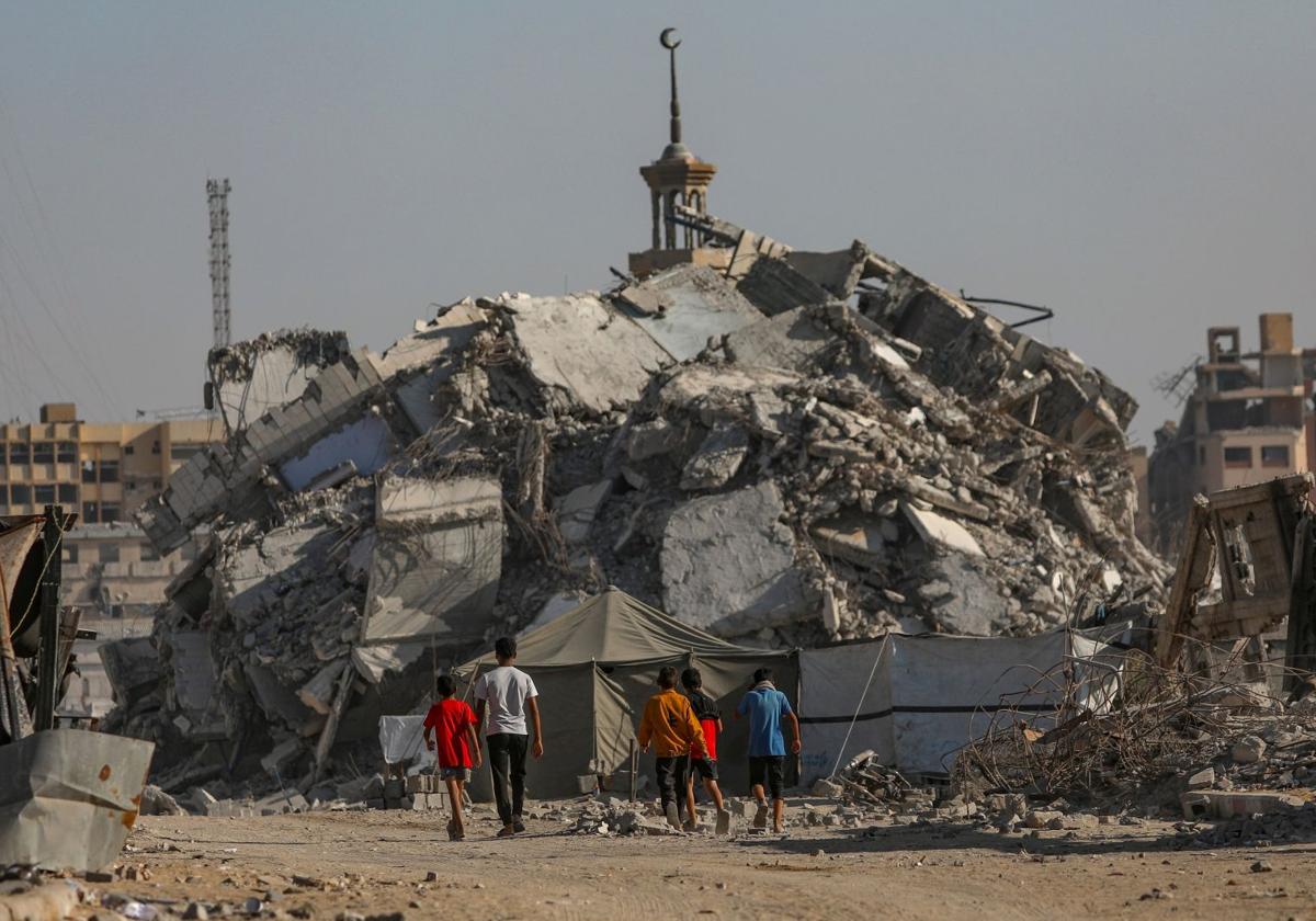 Niños palestinos andan frente a los escombros de Ciudad de Gaza.