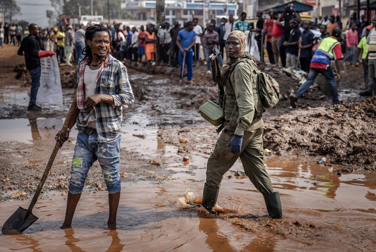 Un miembro del movimiento M23 camina por un charco de agua mientras los residentes limpian las calles de Bukavu