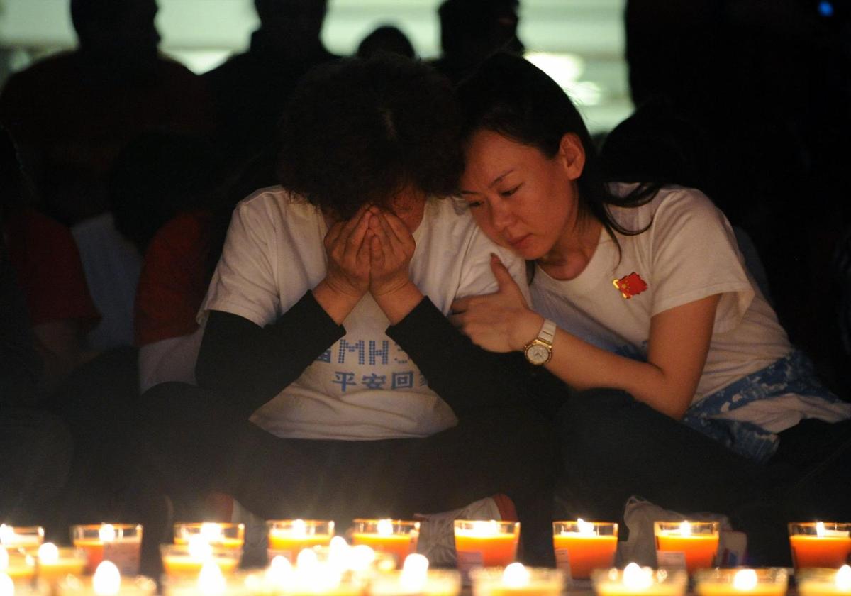 Familiares chinos de los pasajeros del desaparecido vuelo MH370 de Malaysia Airlines rezan frente a unas velas en el Metro Park Hotel de Pekín