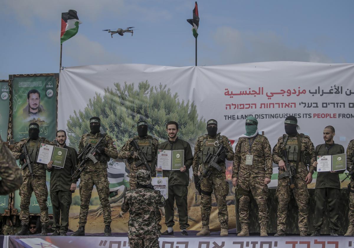 Miembros de Hamás encapuchados junto a rehenes israelíes momentos antes de su liberación