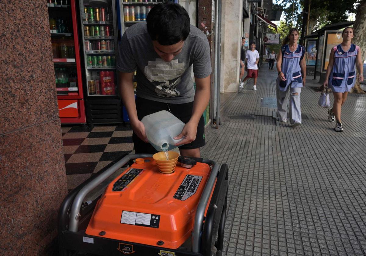 Un hombre poniendo gasolina a un generador eléctrico durante un apagón en Buenos Aires