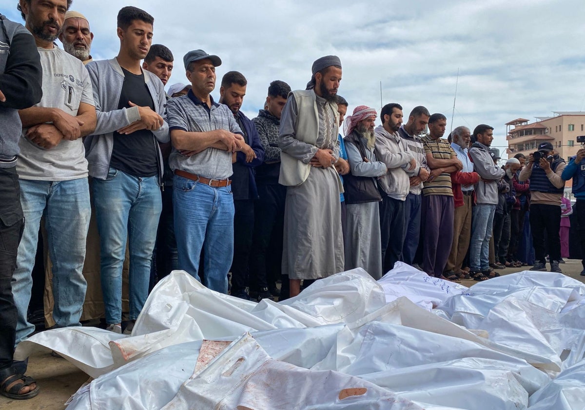 Palestinos rezan junto a los cadáveres de las víctimas de los ataques israelíes, frente al hospital Nasser en Jan Yunis