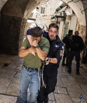 Imagen secundaria 2 - En la primera foto, Israelíes de derecha se reúnen cerca de la Puerta de Damasco durante la 'Marcha de la Bandera' israelí en la Ciudad Vieja de Jerusalén. Un israelí porta una bandera del país en el Día de Jerusalén, en la segunda imagen. Tercera foto: la policía retira a un activista israelí de derecha en la Ciudad Vieja de Jerusalén durante una marcha de banderas por el Día de Jerusalén.