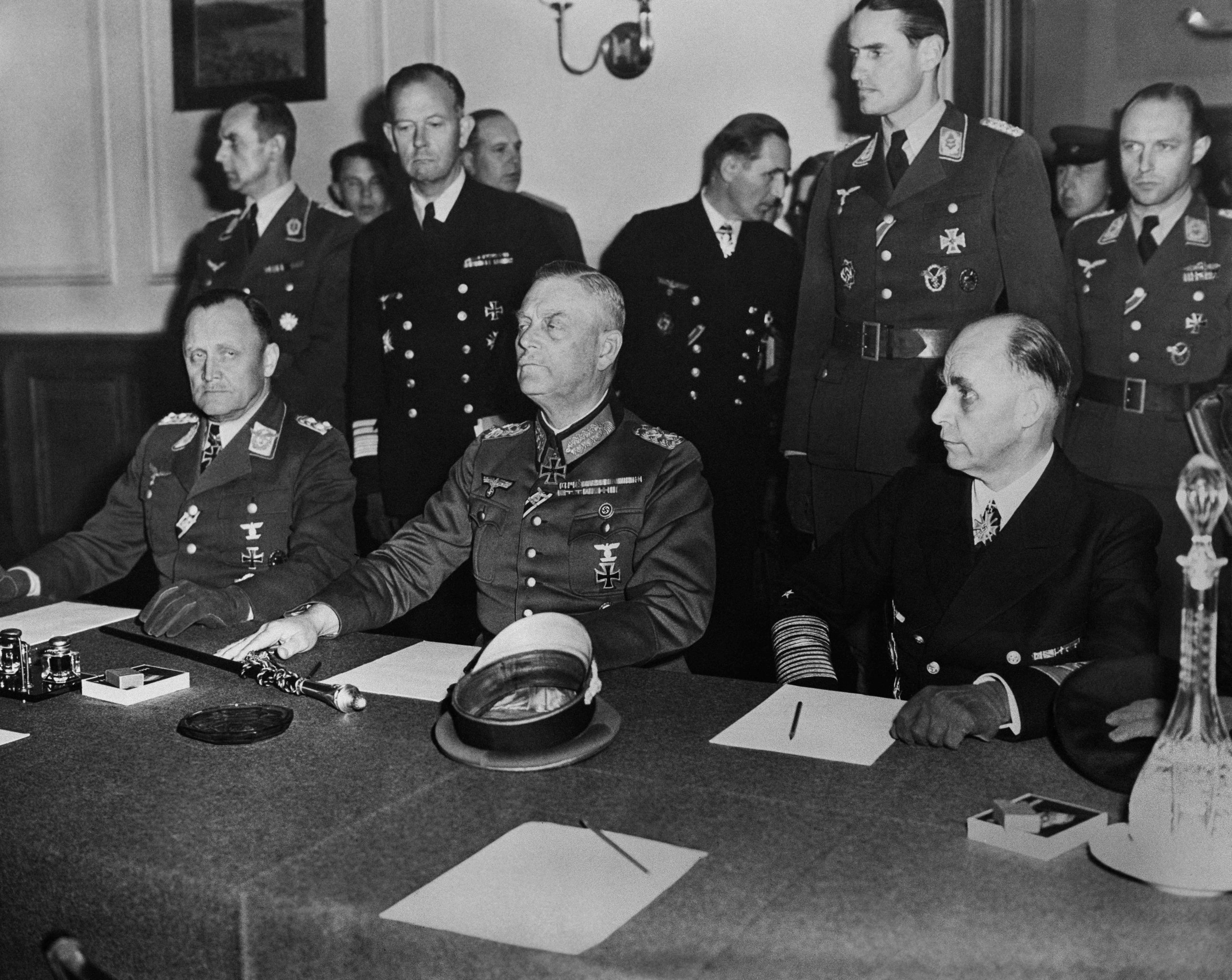 Imagen secundaria 1 - En la primera imagen, el general alemán Hans-Jürgen Stumpff firma el acta definitiva de rendición alemana el 8 de mayo de 1945. En la segunda, generales dialogan sobre la rendición. Soldados soviéticos izan la bandera roja sobre el Reichstag en Berlín, en la tercera foto.