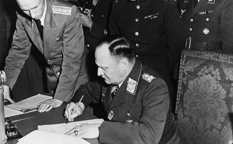 Imagen principal - En la primera imagen, el general alemán Hans-Jürgen Stumpff firma el acta definitiva de rendición alemana el 8 de mayo de 1945. En la segunda, generales dialogan sobre la rendición. Soldados soviéticos izan la bandera roja sobre el Reichstag en Berlín, en la tercera foto.