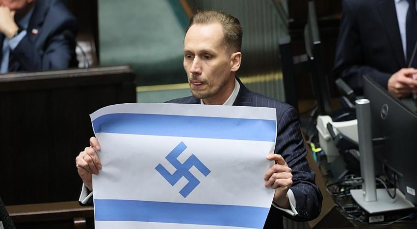 Un diputado polaco de derecha radical muestra en el parlamento la bandera israelí con la esvástica nazi