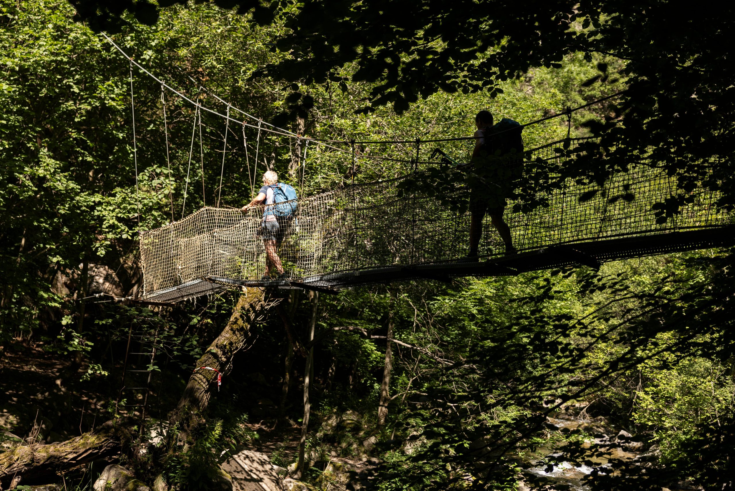 Dos senderista cruzan uno de los puentes colgantes que conforman la ruta de las Gorges de Carançà.