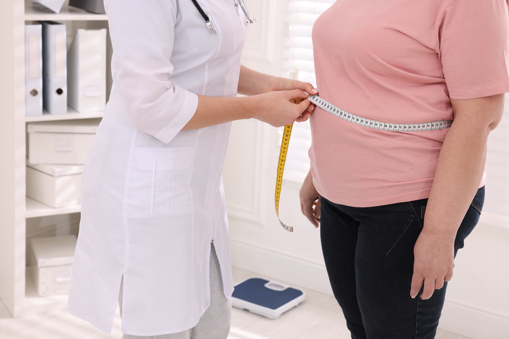 Una nutricionista mide la cintura de una mujer con sobrepeso