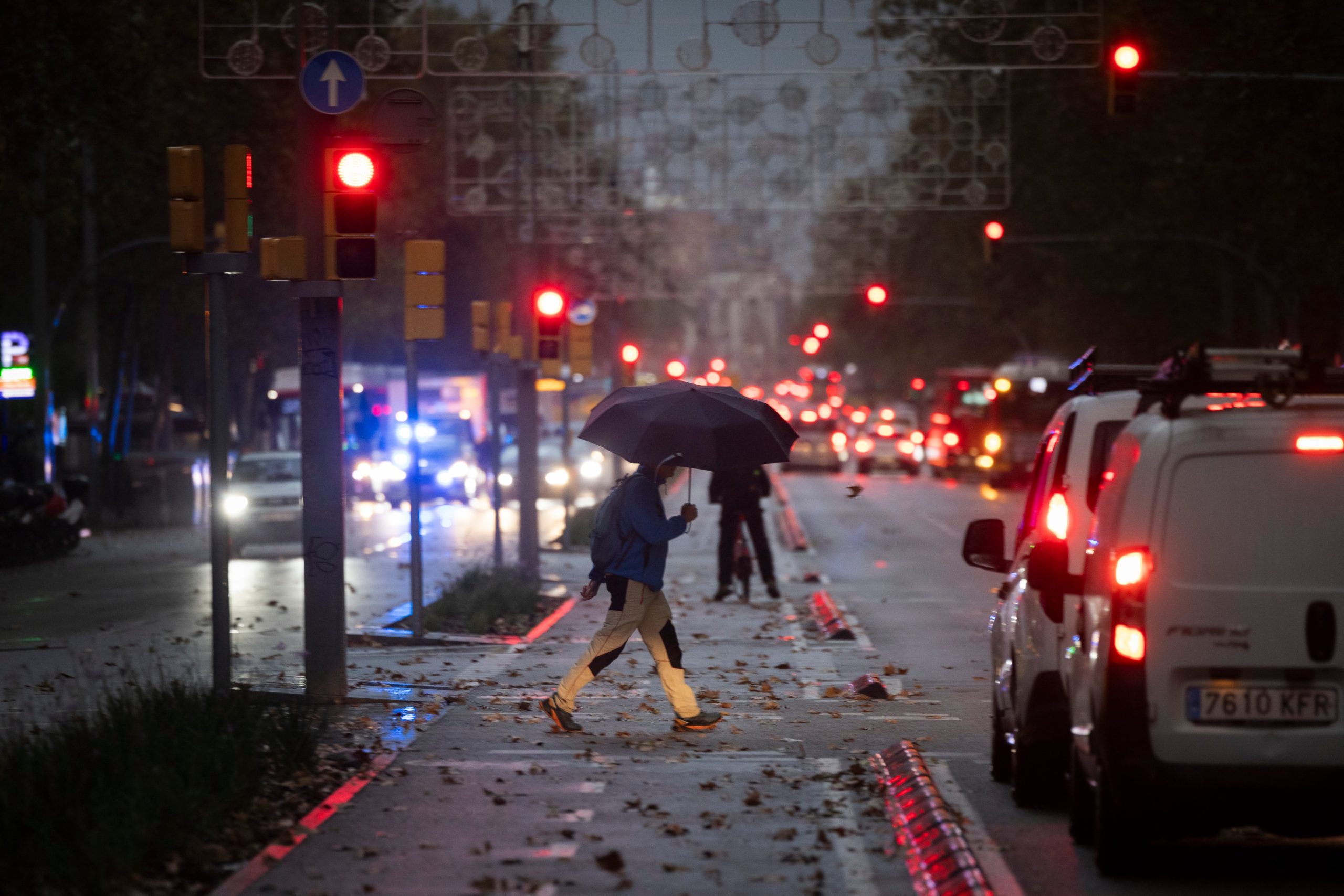 Una persona cruza la avenida Paral·lel este jueves mientras cae una intensa lluvia.