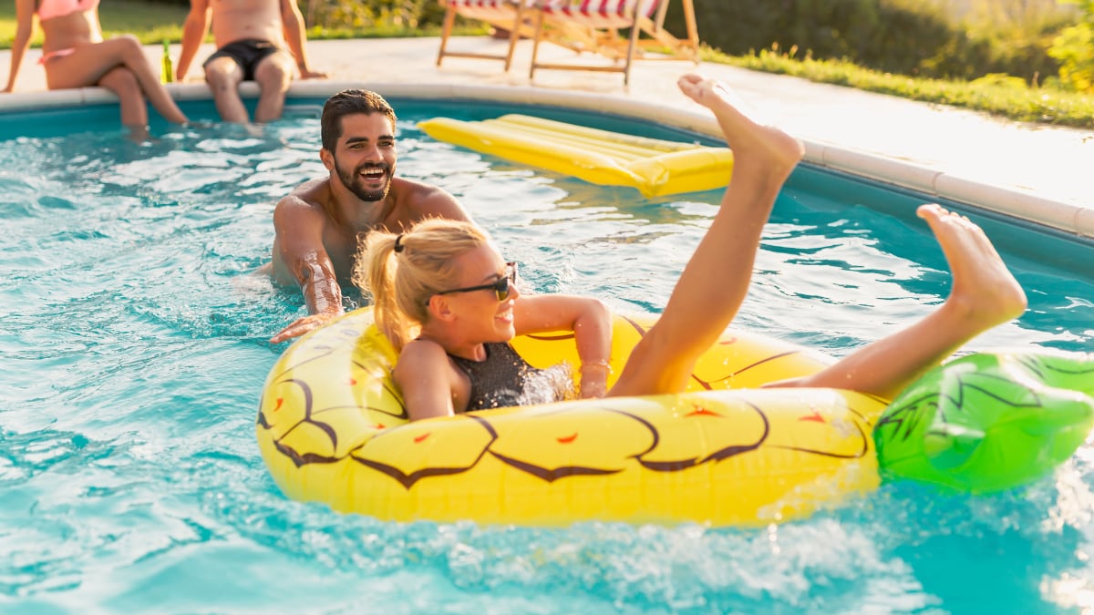 Pareja divirtiéndose en una fiesta junto a la piscina.