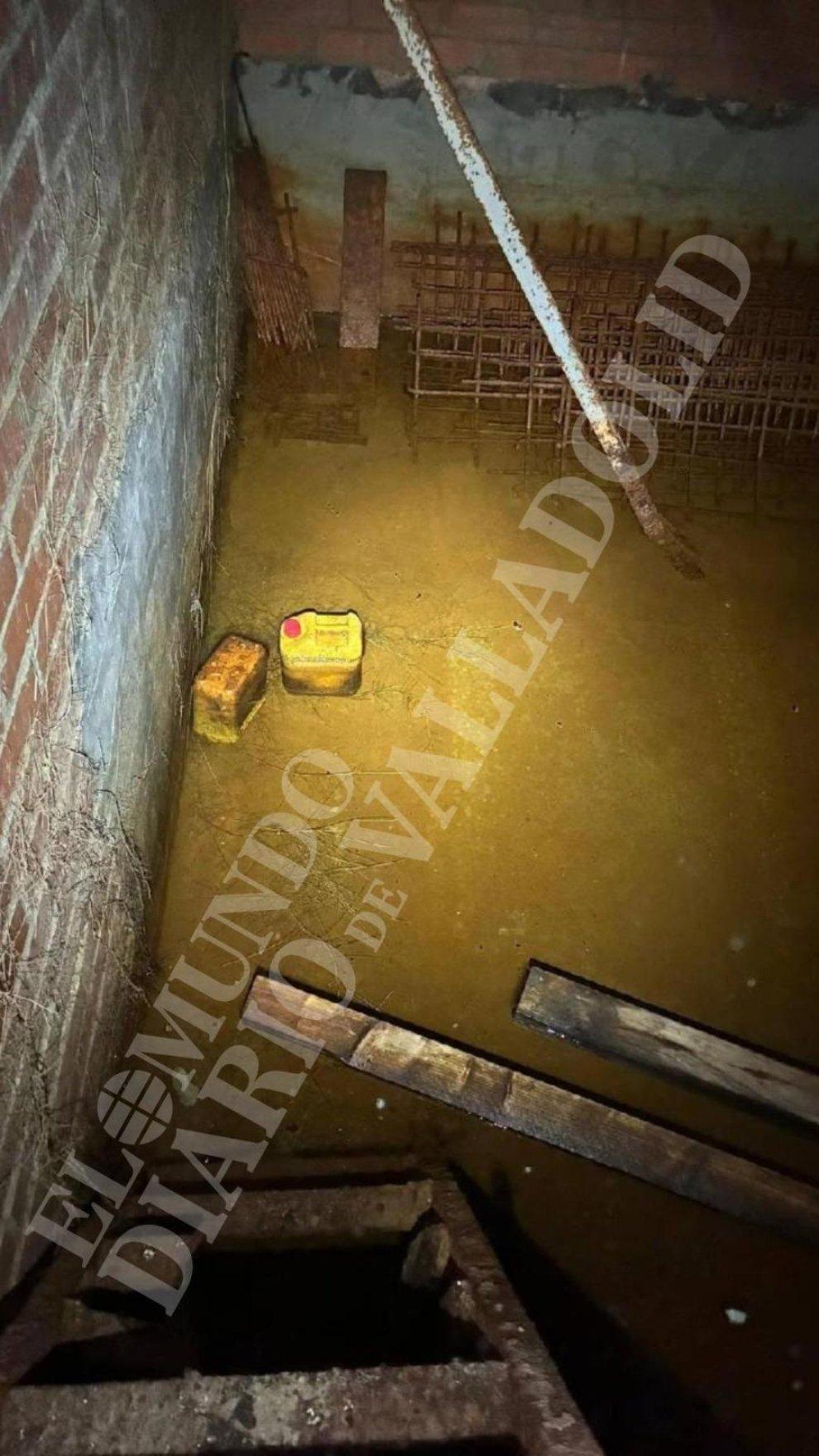 Interior del zulo, donde se observa la ferralla, el agua, unos palos y garrafas de plástico.