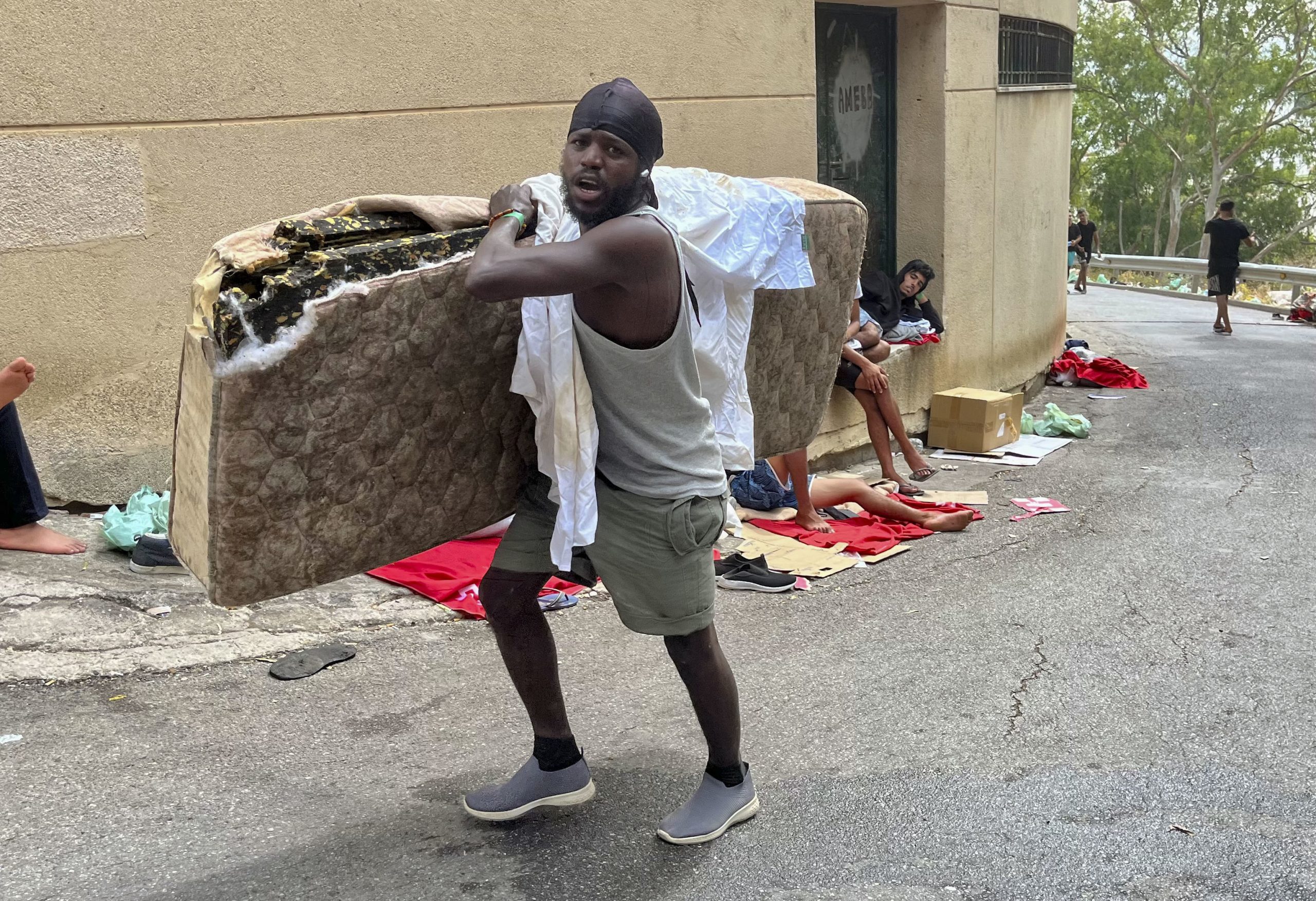 Un migrante carga con un colchón para poder descansar a las puertas del CETI.