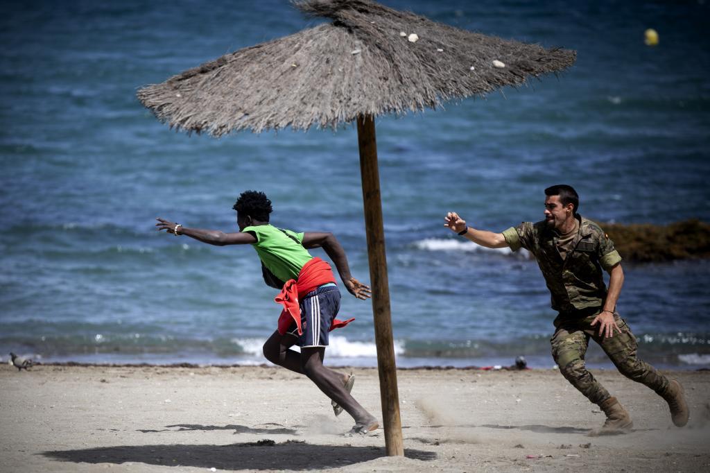 Un militar intenta retener a un inmigrante en la playa de Benítez (Ceuta) para trasladarlo a la frontera.