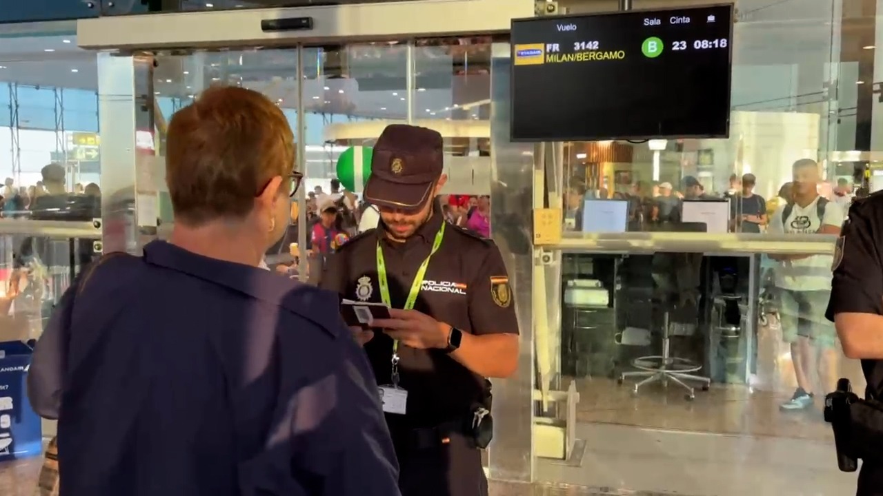 Un policía controla la documentación a un pasajero procedente de Milán.