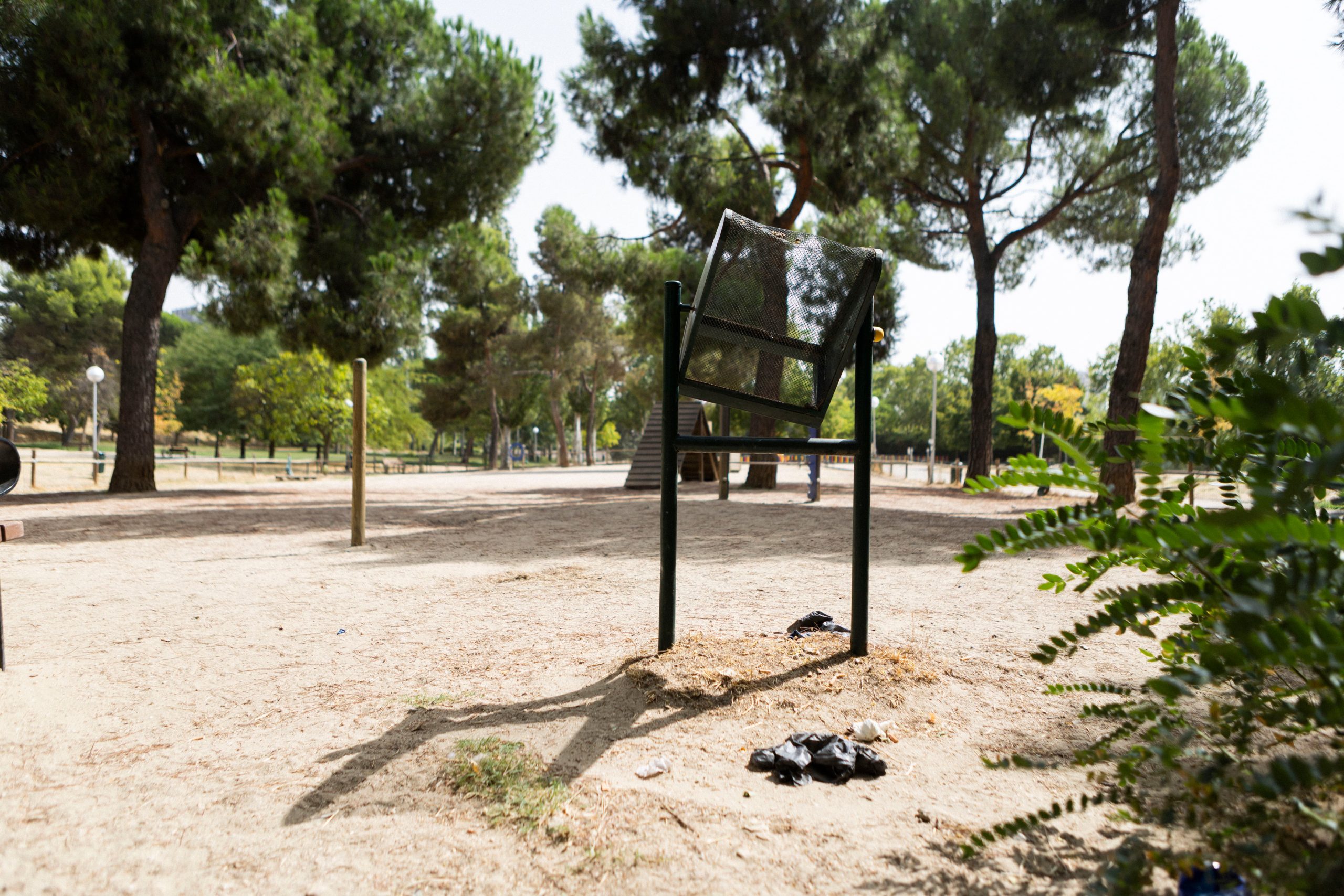Una papelera rota y bolsas con excrementos en el suelo en el área caninas del parque Rodríguez Sahagún.