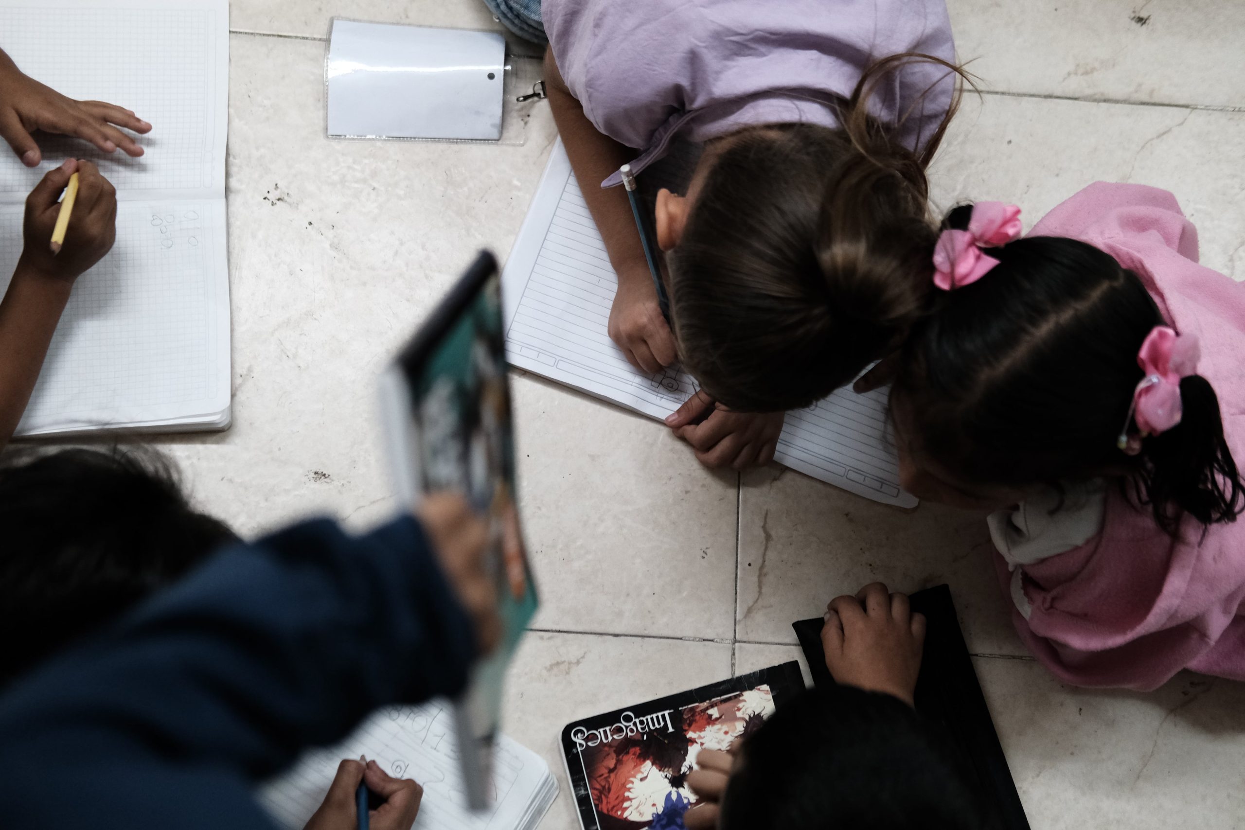 Estudiantes del Colegio Temporal para la Paz en Cúcuta (Colombia) se reúnen para realizar las tareas que puso su profesora para aprender a escribir, en febrero de 2025.
