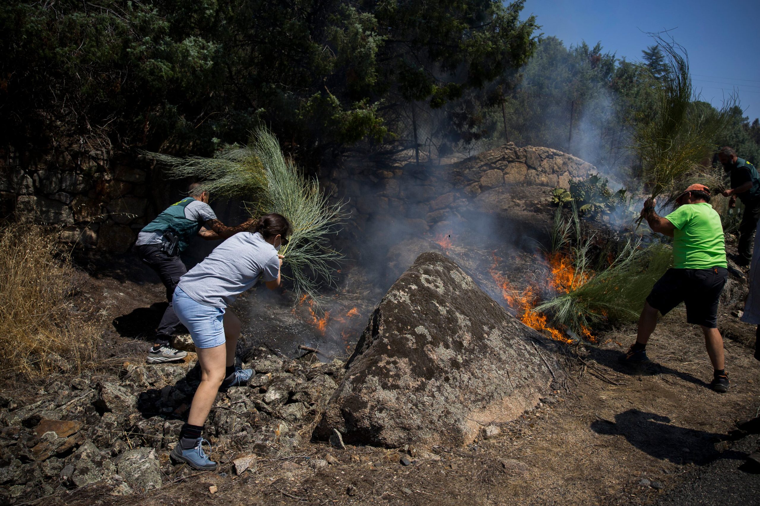 Vecinos y Guardia Civil luchan contra el fuego en un pequeño conato que se ha reactivado en la zona afectada por el fuego en Navaluenga.