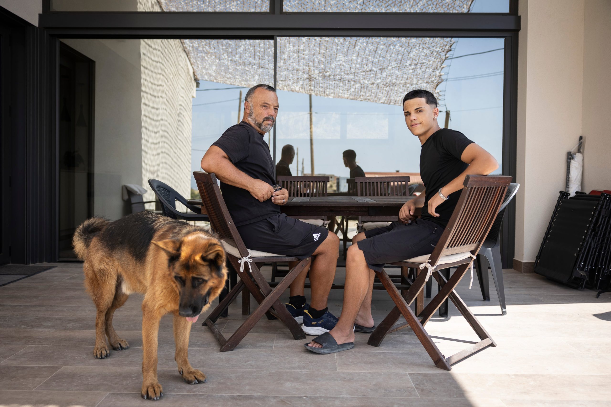 Alex Codonyer y su hijo Alan sentados en la mesa de madera de su casa, el único mueble que sobrevivió al incendio de 2022