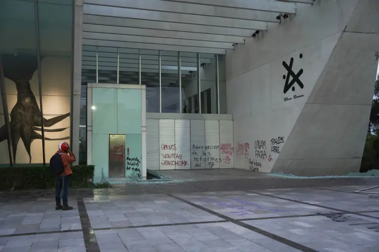 Un hombre mira un grafiti pintado por manifestantes que asisten a una manifestación contra la gentrificación en una pared del Museo de Arte Contemporáneo de la Ciudad de México.