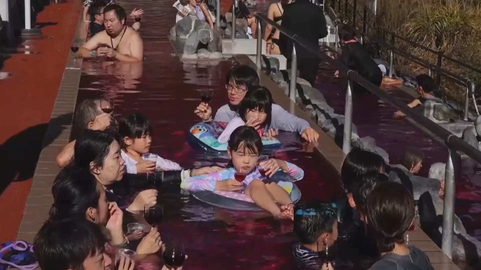 La insólita experiencia de unos japoneses: beben vino y se bañan en una piscina con agua de color rojo