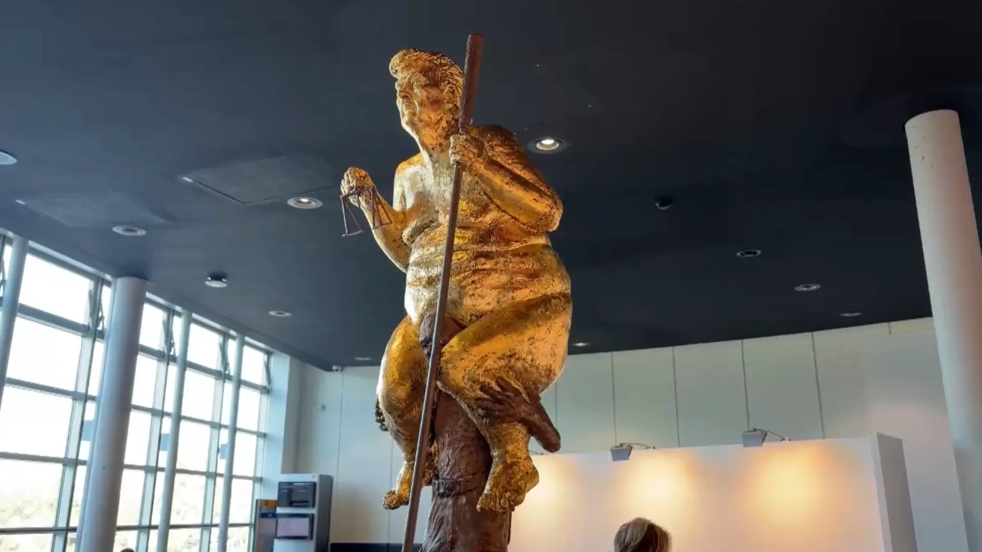 Una polémica estatua dorada de Trump desnudo con un palo de golf y encima de un hombre sorprende al Parlamento Europeo